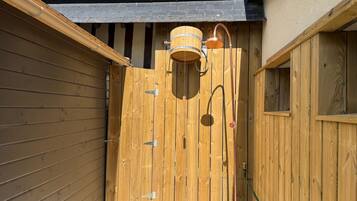 A wooden gate with a metal lock, a wooden barrel, and a hose connected to a metal stand.
