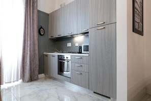 A modern kitchen with grey cabinets, stainless steel appliances, and a marble floor. - San Niccolo' Luxury Apartment (Firenze)