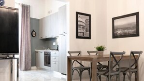 Una cocina moderna con armarios grises, una mesa de comedor con cuatro sillas y dos fotografías en blanco y negro de un paisaje urbano en la pared.