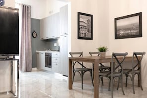 Een moderne keuken met grijze kastjes, een eettafel met vier stoelen, en twee zwart-wit foto’s van een stadsgezicht aan de muur.