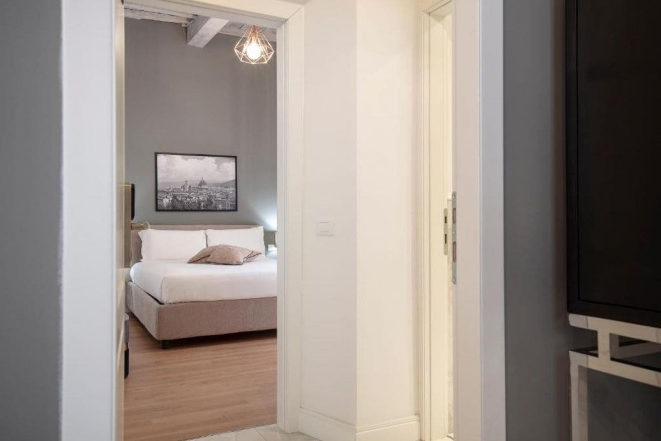 Un dormitorio con una cama, un cuadro en la pared y un televisor sobre un mueble.
