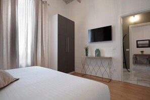 Ein Schlafzimmer mit Bett, Kleiderschrank, Fernseher und einem kleinen Tisch mit Dekoration.