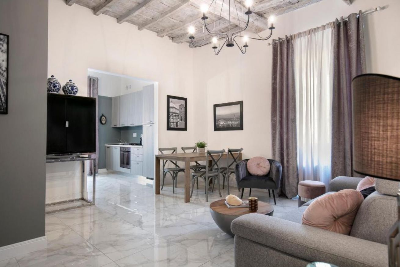 A modern living room with a sofa, a coffee table, and a dining area with a table and chairs.