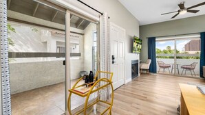 A spacious room with a sliding glass door leading to a balcony, a ceiling fan, and a wooden table. - Old Town Condo Paradise | Pool | Hot tub | Location (Scottsdale)
