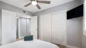 A bedroom with a bed, a ceiling fan, and white doors. - Old Town Condo Paradise | Pool | Hot tub | Location (Scottsdale)