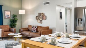 A modern living room with a brown leather sofa, a coffee table, and a dining table set for four. - Old Town Condo Paradise | Pool | Hot tub | Location (Scottsdale)