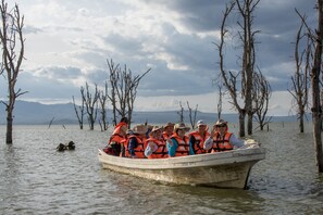 Un grupo de personas en un bote, con chalecos salvavidas, rodeado de árboles y agua.
