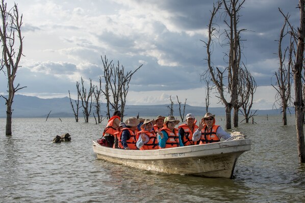 Un grupo de personas en un bote, con chalecos salvavidas, rodeado de árboles y agua.