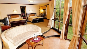 A hotel room with two beds, a sofa, a small table with a bottle and glasses, and a large window with curtains. - Lake Naivasha Sopa Resort (Naivasha)