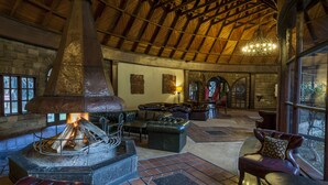 A rustic interior with a stone fireplace, leather furniture, and a high wooden ceiling. - Lake Naivasha Sopa Resort (Naivasha)