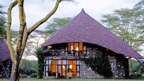 A stone house with a conical roof, large windows, and a balcony. - Lake Naivasha Sopa Resort (Naivasha)