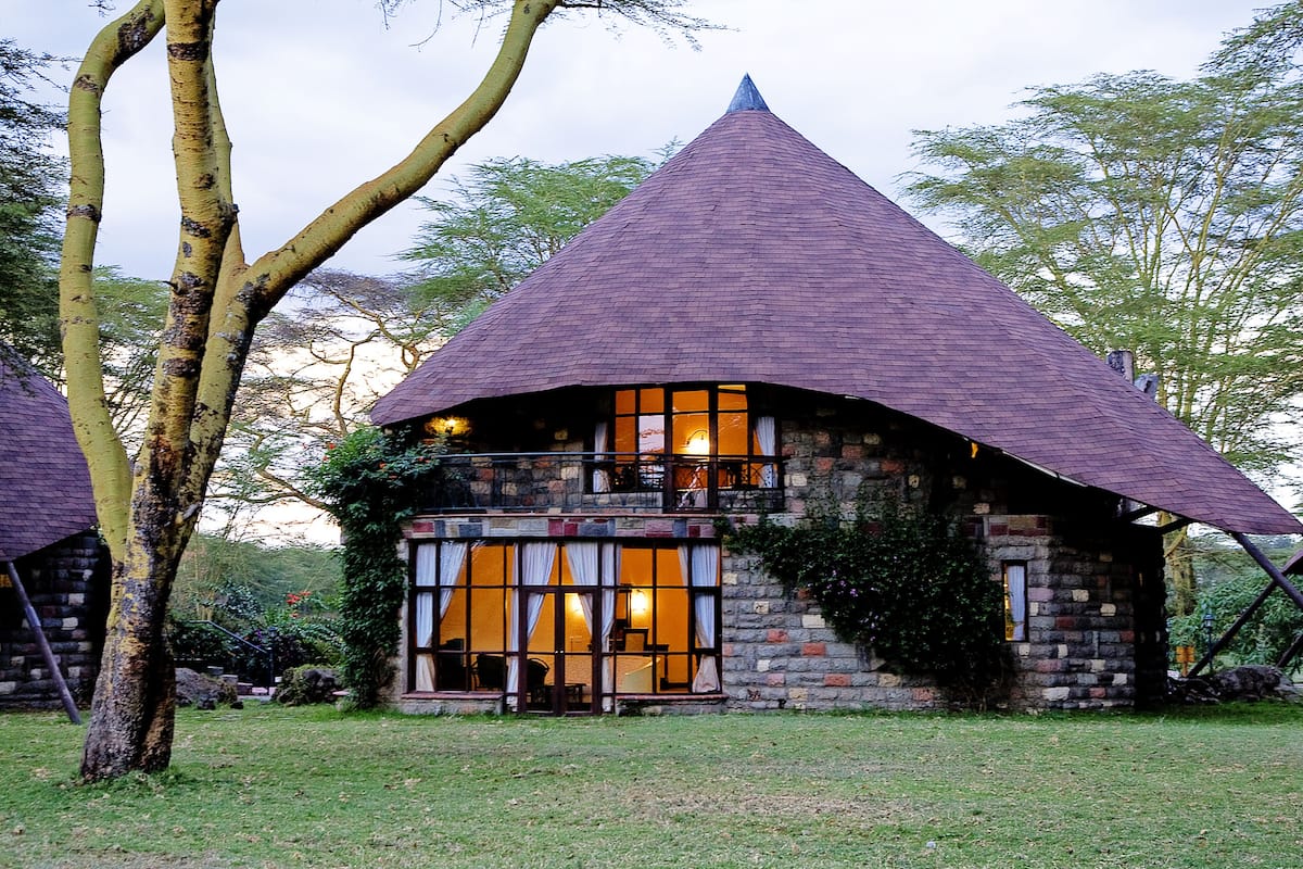 A stone house with a conical roof, large windows, and a balcony.