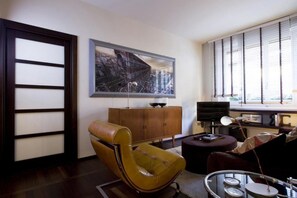 Un salon moderne avec un fauteuil en cuir marron, un meuble en bois et un grand tableau abstrait accroché au mur.