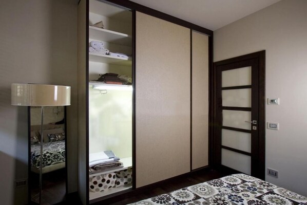 A bedroom with a bed, a bedside table with a lamp, a wardrobe, and a door.