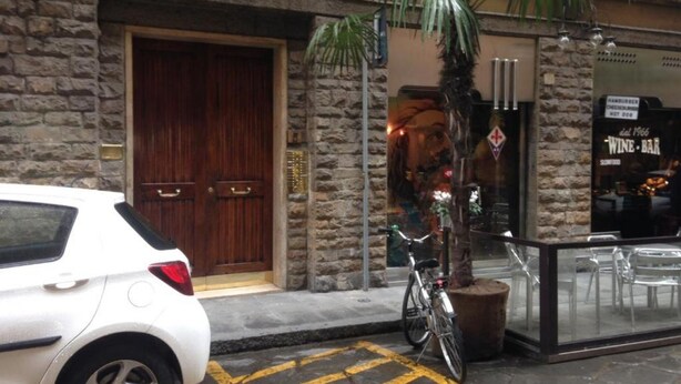 A white car parked in front of a building with a stone facade and a wooden door.