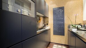 A modern kitchen with dark cabinetry, a stainless steel range hood, and a chalkboard menu on the wall.