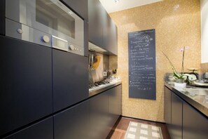 Une cuisine moderne avec des meubles de couleur sombre, une hotte de cuisinière en acier inoxydable et un tableau noir servant de menu, fixé au mur.