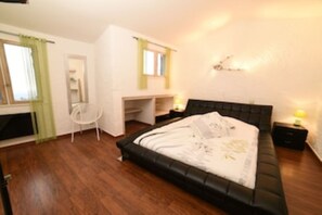 A bedroom with a bed, a desk, and a chair.
