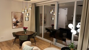 Un salon moderne comprenant un coin repas, un canapé, une petite table avec une plante et une grande fenêtre avec des rideaux.