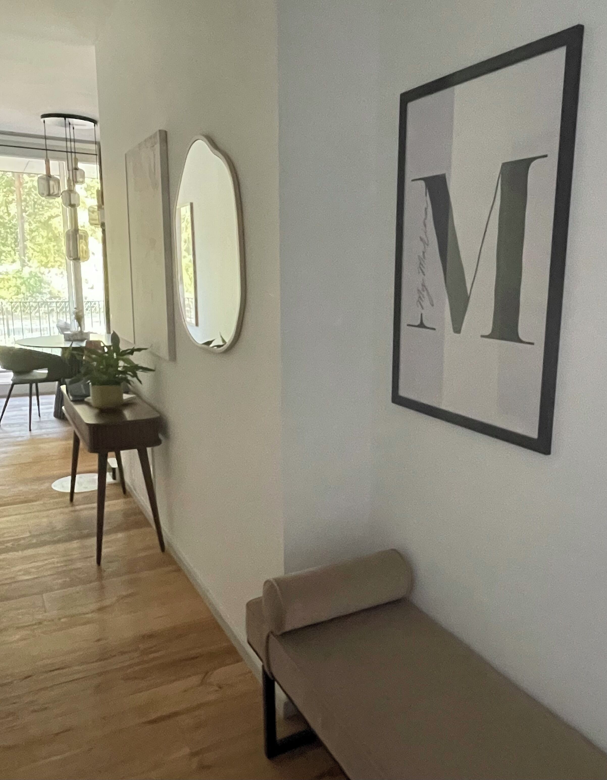 Un interno moderno con una panca, un tavolo con una pianta e opere d'arte incorniciate al muro.