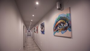 A hallway with artworks on the walls, recessed lighting, and a tiled floor. - DORM BG (Stara Zagora)