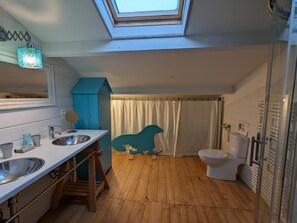 Une petite salle de bain avec un puits de lumière, un lavabo, des toilettes et une douche.
