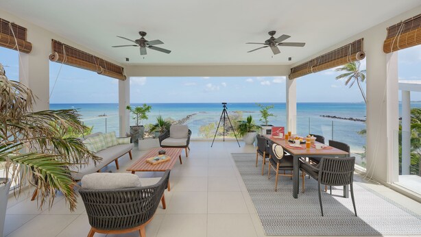 A spacious patio with a dining area, seating, and a view of the ocean. - Otera 2 Residence (Trou aux Biches)