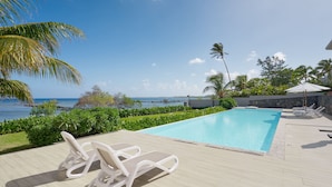 A pool area with lounge chairs, a view of the ocean, and a clear sky. - Otera 2 Residence (Trou aux Biches)