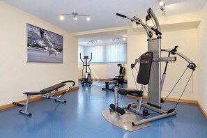 Un gimnasio con equipamiento de ejercicio, una banca y un cuadro en la pared.