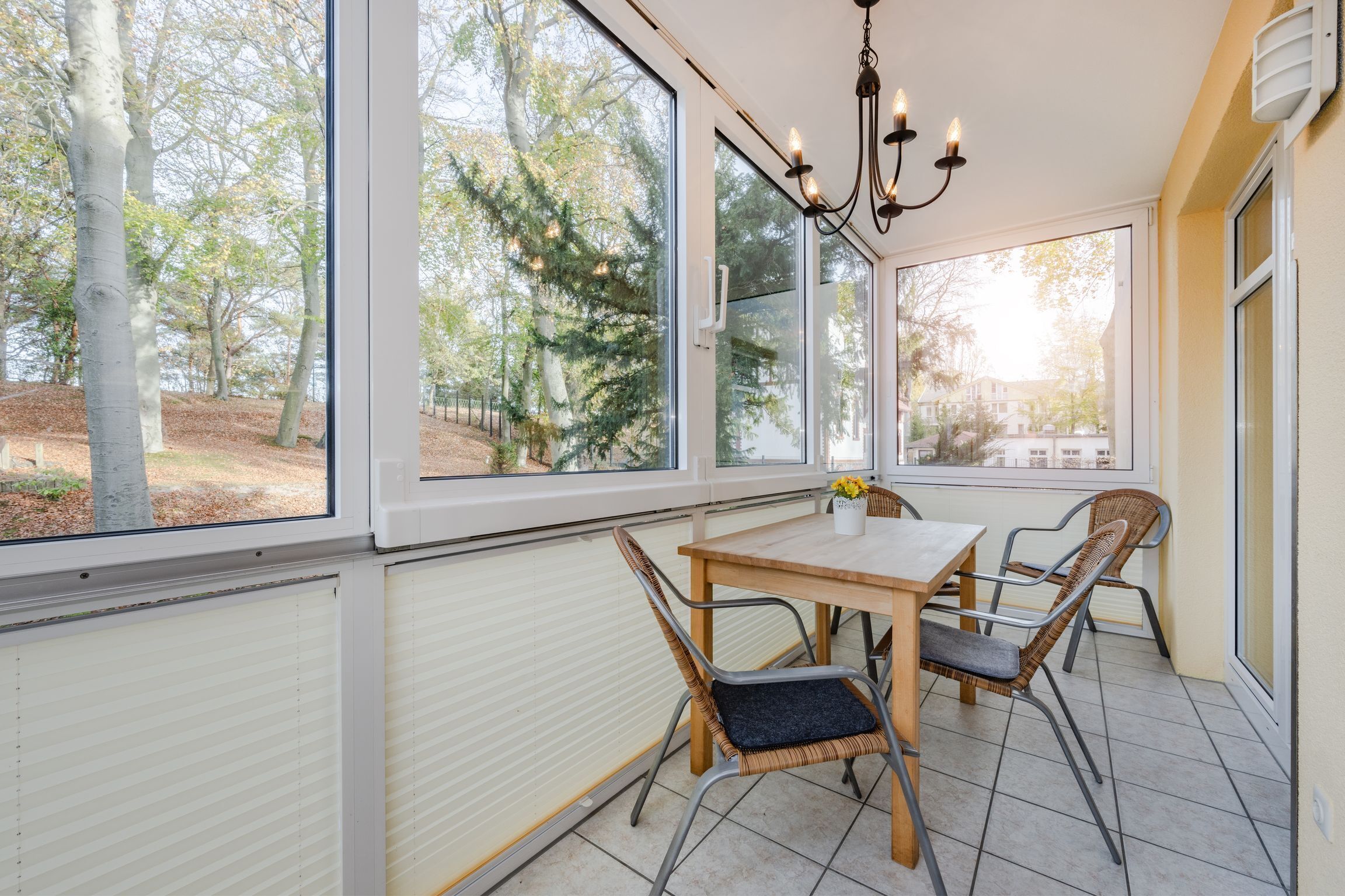 A dining area with a table and chairs, large windows, and a view of trees.