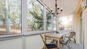 Comedor con mesa y sillas, ventanas amplias y vista a árboles.