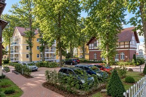Un quartier résidentiel avec des immeubles à plusieurs étages, des voitures garées et un trottoir dallé.