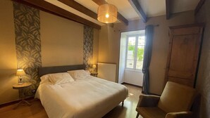 A bedroom with a bed, bedside lamps, a chair, a window, and a radiator.