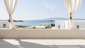 A balcony with white curtains, a clear view of the sea, and buildings in the background. - Villa Dia, Mikri Vigla, Panagia Parthena Beach (Naxos)