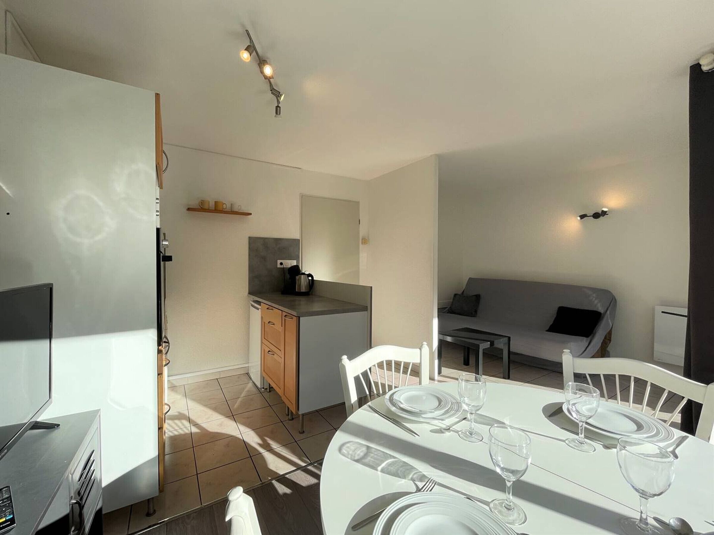 A compact living space with a dining area, kitchenette, and a sofa.