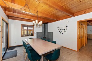 A dining area with a wooden table and chairs, a fireplace, and a chandelier.