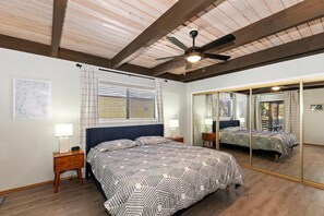 Ein Schlafzimmer mit einem Bett, Nachttischen, einem Deckenventilator und einem großen Spiegel.