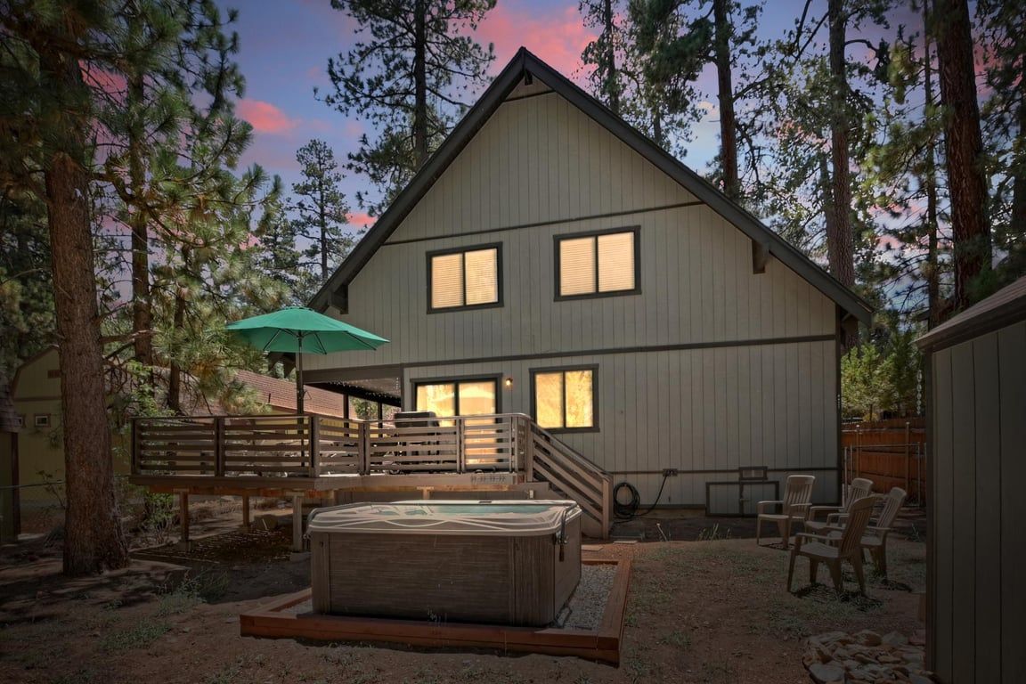 A two-story house with a deck, a hot tub, and outdoor seating.