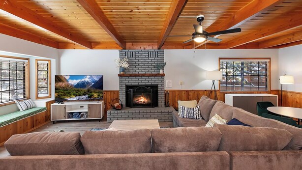 Ein gemütliches Wohnzimmer mit Kamin, Holzbalkendecke, einer Couch und einem Fernseher.