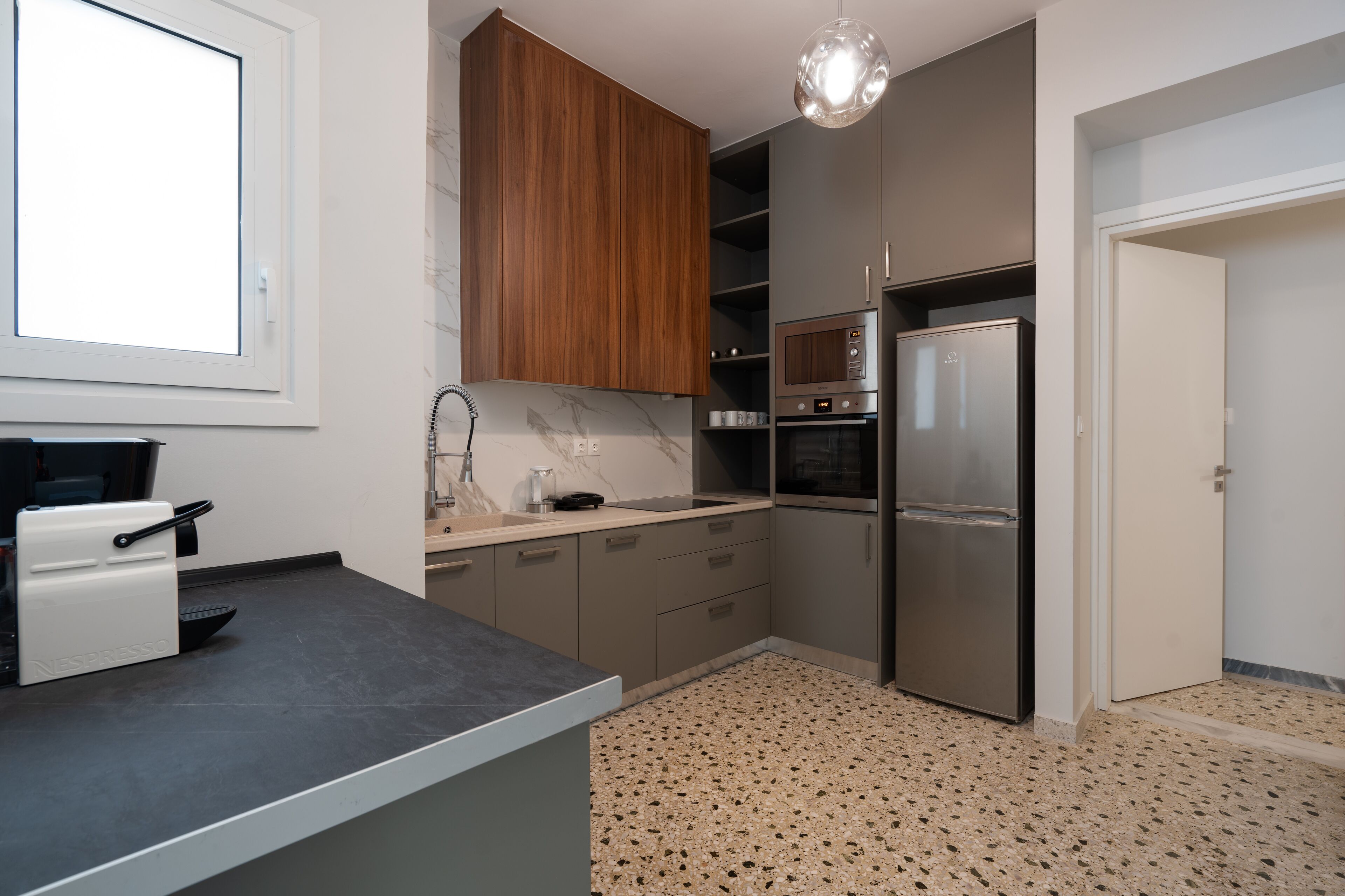 A modern kitchen with a built-in espresso machine, a microwave, oven, and a refrigerator.