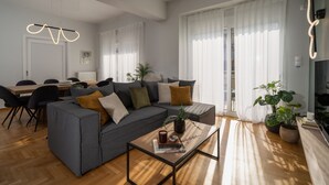 A modern living room with a grey sofa, a wooden coffee table, and a dining area with a table and chairs. - Deluxe 4 Bedrooms Apartment in Athens Center (Athens)