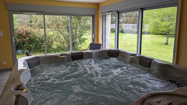 A hot tub with a view of a garden through large windows. - Comfortable house with private garden, internet, parking (Agris)