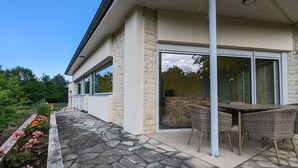 A modern house with a stone patio, a dining area with wicker furniture, and large sliding glass doors. - Comfortable house with private garden, internet, parking (Agris)