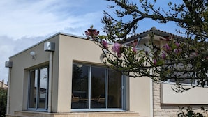 A modern building with large glass windows, a flat roof, and a stone facade. - Comfortable house with private garden, internet, parking (Agris)