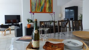Un coin repas avec une table dressée pour deux personnes, agrémenté d’une bouteille de vin, de verres et d’assiettes.