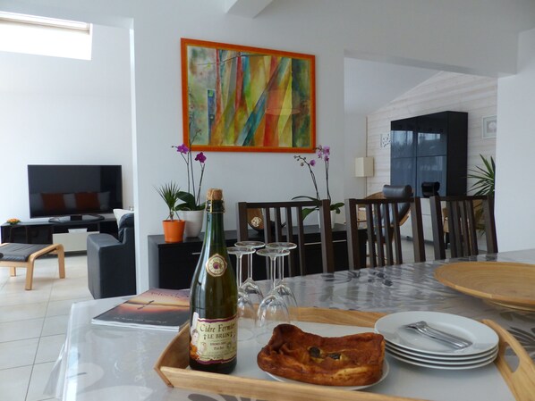 Un coin repas avec une table dressée pour deux personnes, agrémenté d’une bouteille de vin, de verres et d’assiettes.