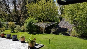 Un jardin agrémenté de plantes en pot, d’un hamac et d’une petite structure ressemblant à une maison.
