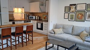 Une cuisine compacte avec un coin bar, un canapé gris et une table basse.