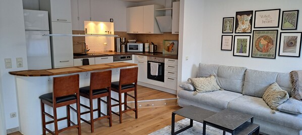 Eine kompakte Küche mit Bar, ein graues Sofa und ein Couchtisch.