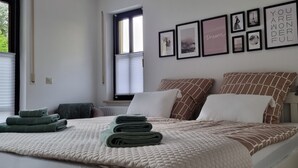 Un lit bien fait, avec une couverture et des oreillers, une lampe de chevet et une fenêtre avec des stores.